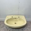 Cream wash basin made by Armitage Shanks with 2 tap holes on white backdrop with bathroom tiles