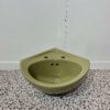 Small avocado corner basin with white backdrop and bathroom tiles