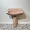 Pink basin and pedestal with white backdrop and bathroom tiles