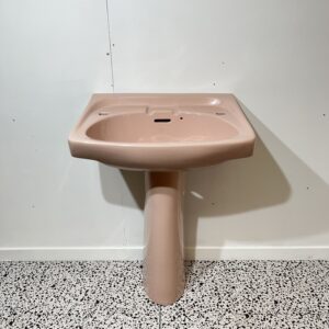 Pink basin and pedestal with white backdrop and bathroom tiles