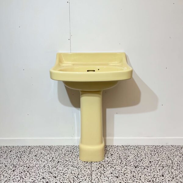 Yellow 1950s vintage basin and pedestal on white backdrop with bathroom tiles