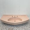 large pink retro basin with 3 tap holes on white backdrop and retro bathroom tiles