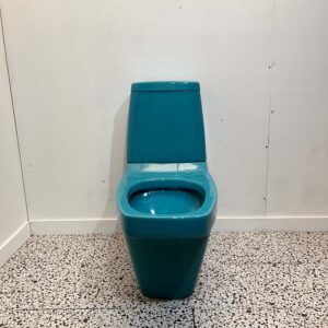 Blue square close coupled toilet with white backdrop and bathroom tiles