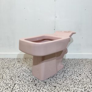 Square pink toilet pan with white backdrop and bathroom tiles